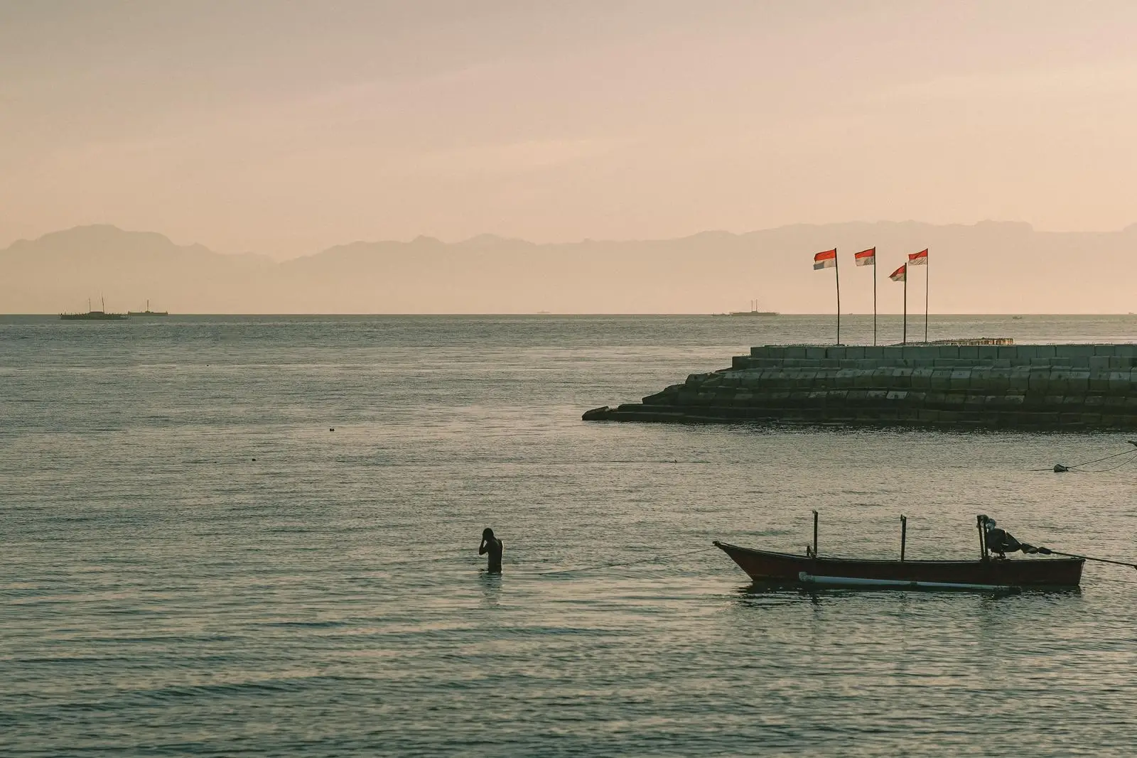 Sunset on the north coast of Java with fishing boats and the Indonesian red-and-white flag